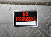no trespassing warning sign on iron chainlink fence