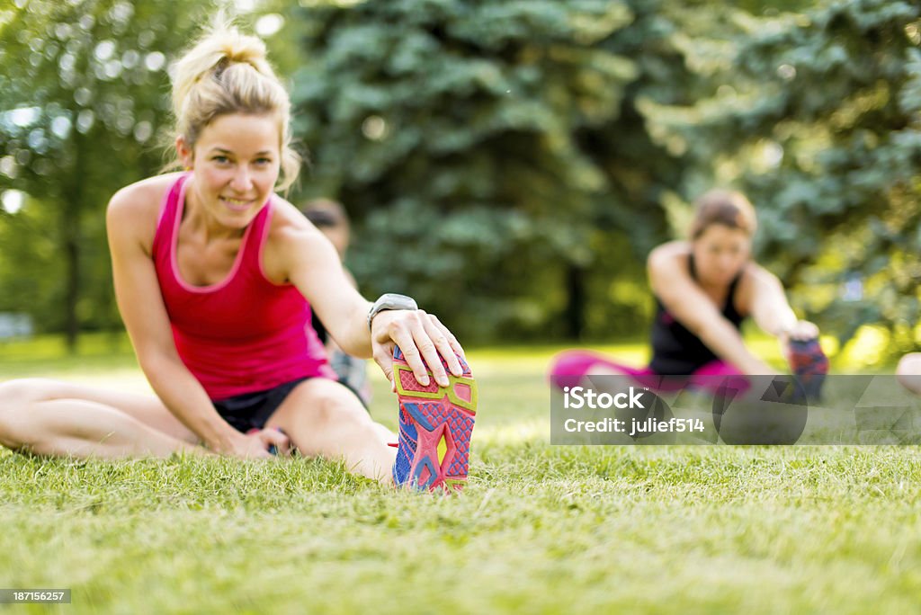 young woman stetching before a jog Portait of a blond girl getting streching her legs before running outdoors Active Lifestyle Stock Photo