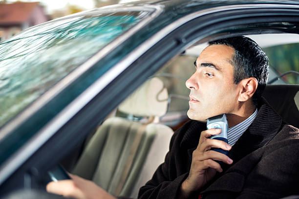 Businessman In Hurry Businessman sitting in a car, shaving his face with an electric shaver. shaving while driving stock pictures, royalty-free photos & images