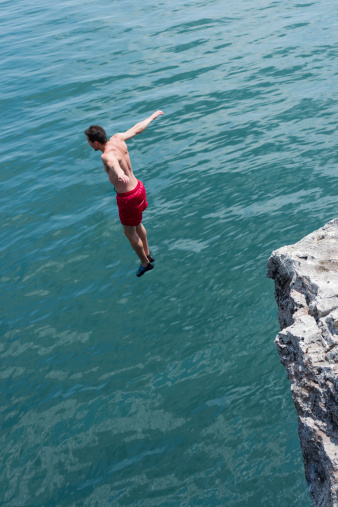 Young Man Taking a Plunge into the Ocean from a  High Cliff