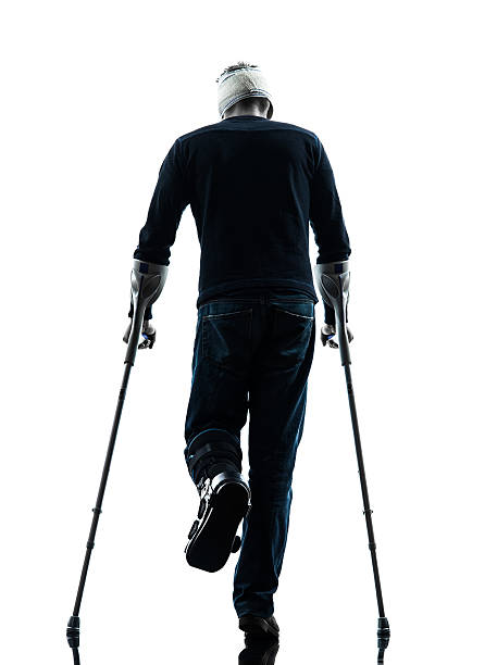 istock injured man walking rear view with crutches silhouette 187156836