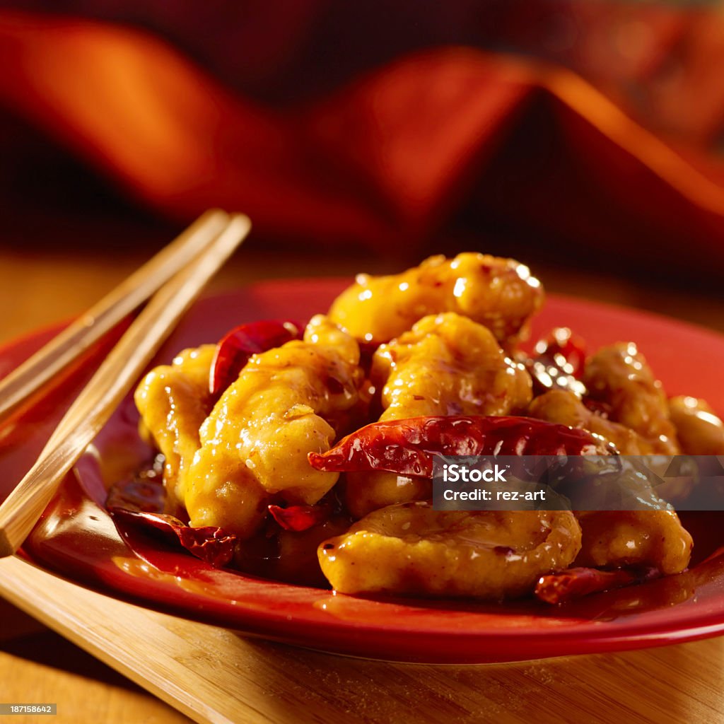 Close-up of General Tso chicken dish on red with chopsticks Eating general tso's chicken with chopsticks close up photo. Asian Culture Stock Photo