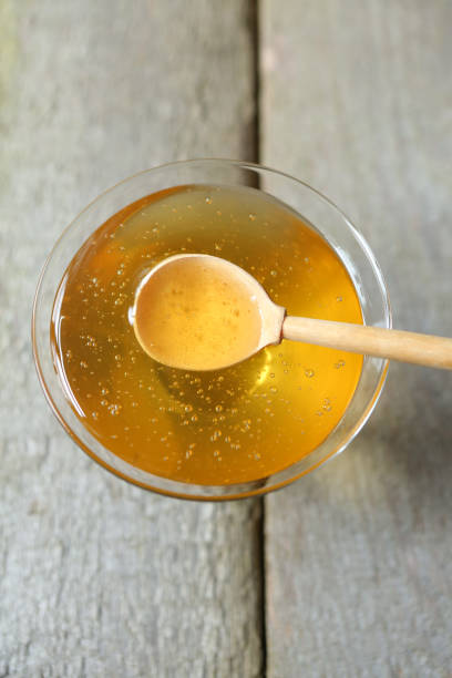 istock Young light floral honey is poured into a glass vase. 1871592528