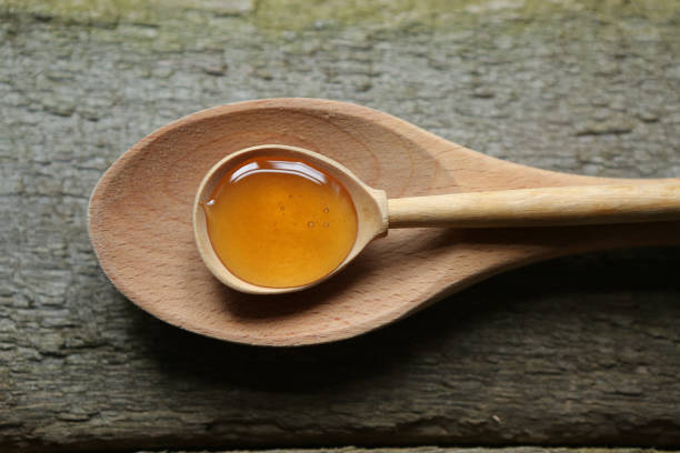 istock Young light floral honey is poured into a wooden spoon. 1871607719