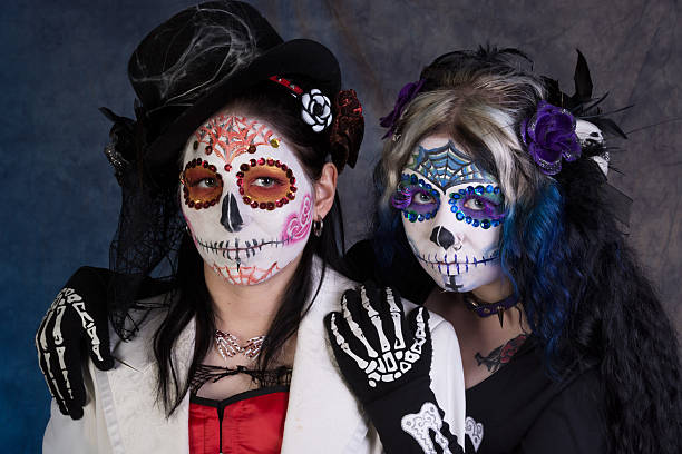 istock Two women in sugar skull makeup on blue/purple background. 187162896
