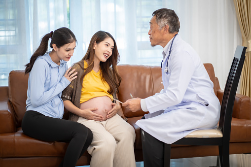 Asian woman who is pregnant Currently receiving a health check from a doctor at home.