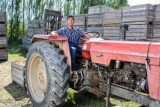 Confident young man driving a tractor across farmland, engaged in agricultural work. Rural lifestyle and hands-on farming in a natural outdoor setting.