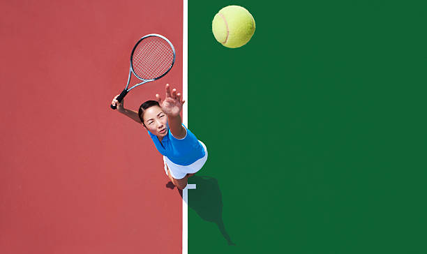 woman tennis player serving Young Asian woman serving tennis ball, photographed from directly above her. serving sport stock pictures, royalty-free photos & images