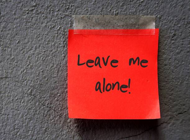 istock A red note with text written LEAVE ME ALONE sticking on dark grey wall with blank copy space. Asking other  for private time or to stop talking / stop being near/ stop interfering. 1871659114