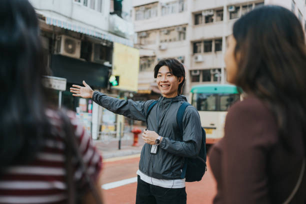 A smiling Chinese tour guide pointing directions to tourists