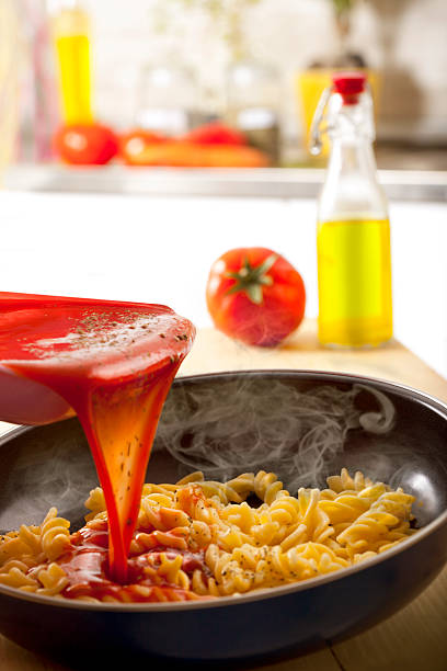 Pouring marinara sauce onto pasta