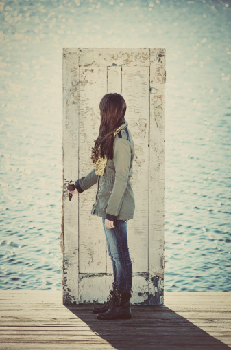 A young woman opens a doorway to the sea. Mahone Bay Saltylypse 2013.