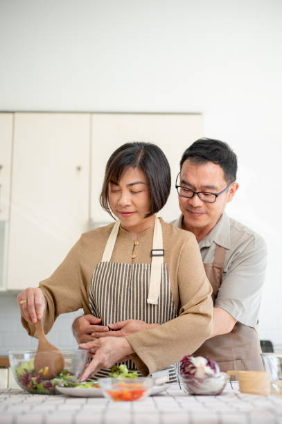 istock A caring, romantic Asian husband is embracing his wife from the back while she is cooking. 1871668795