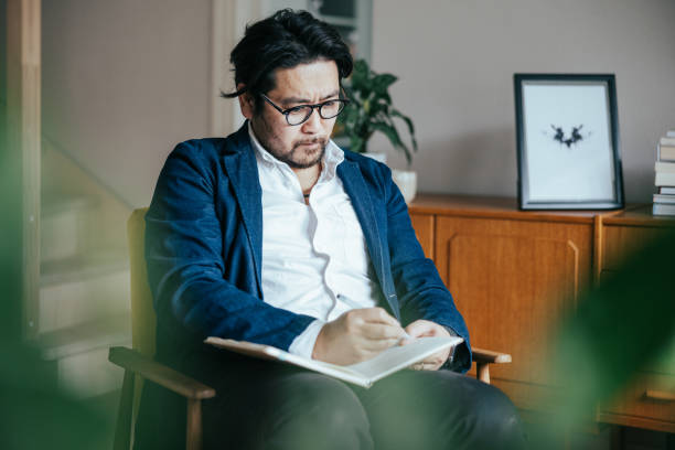 istock Japanese therapist writing notes from therapy session with patient 1871689364