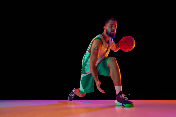 istock Skill and athleticism. Basketball player executing perfect slam dunk, illustration strength and precision against black background in neon light. 1871696630