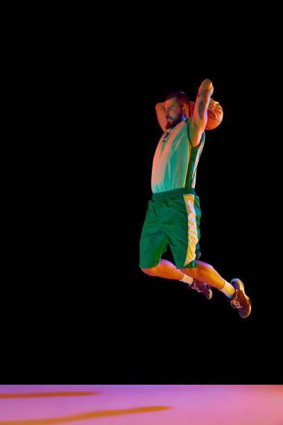istock Powerful moment frozen in time, basketball player commitment to perfect slam dunk against black background in neon light. 1871696641