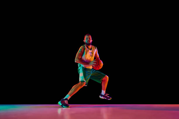 istock Basketball player, athletic man executing perfect slam dunk, illustration strength and precision against black background in neon light. 1871696647