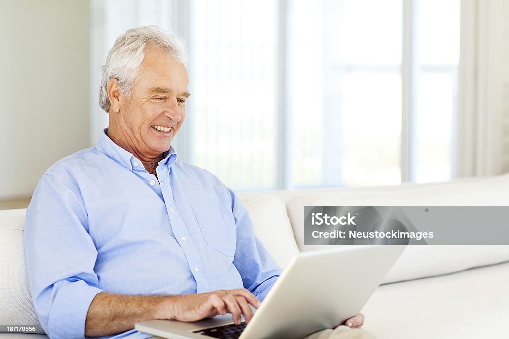 Uomo anziano utilizzando il computer portatile a casa - Foto stock royalty-free di Computer portatile