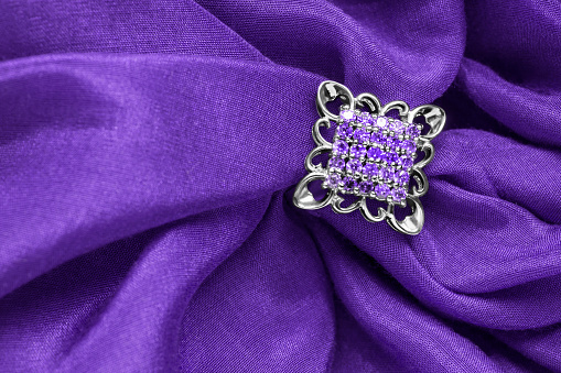 Amethyst silver brooch on purple draped fabric background
