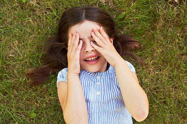 istock Young girl lying on grass covering eyes 187170794