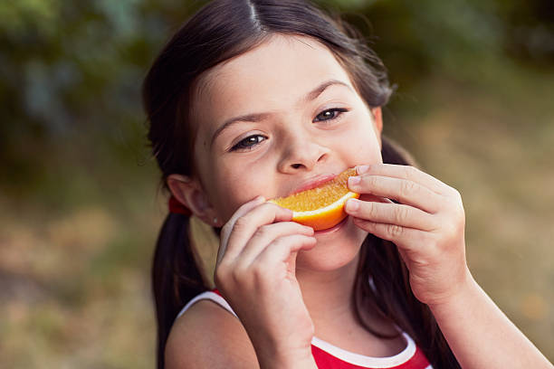 istock Young girl eating orange, portrait 187170855