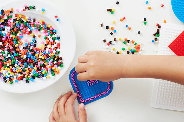 Young girl playing with beads, overhead view