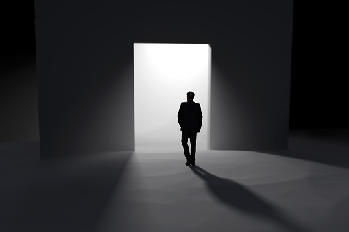 Rear view of single young man walking through a dark tunnel