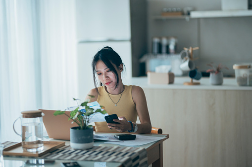 Upset woman thinking about high prices while looking at utilities, gas, electricity, rental charges, water bill due to inflation and crisis. Planning personal budget while sitting in kitchen. Weighing options on how to save money