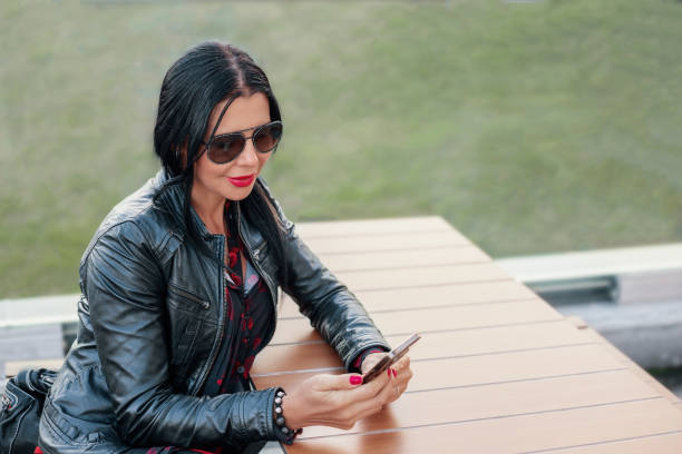 istock Woman sitting at a table and looking at phone 1871766446