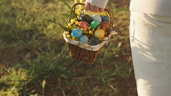 A walk behind a woman in white carrying a basket of painted Easter eggs. Sunny forest at dawn.