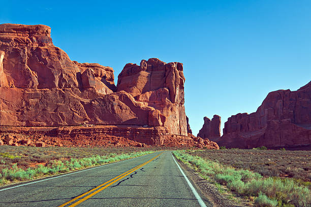 Arches Road at Utah National Park Clear blue sky over Arches Road at Utah National Park, US. single yellow line sunlight usa utah stock pictures, royalty-free photos & images