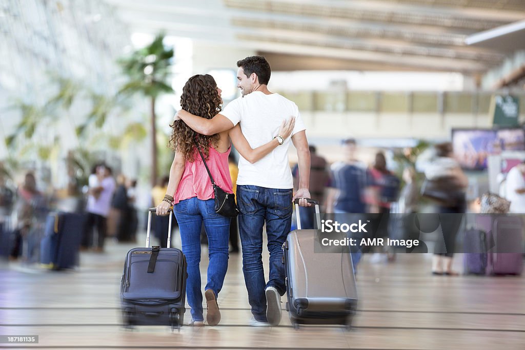 Couple with suitcases inside airport Young couple in a crowded airport, walking to their gate. Couple - Relationship Stock Photo