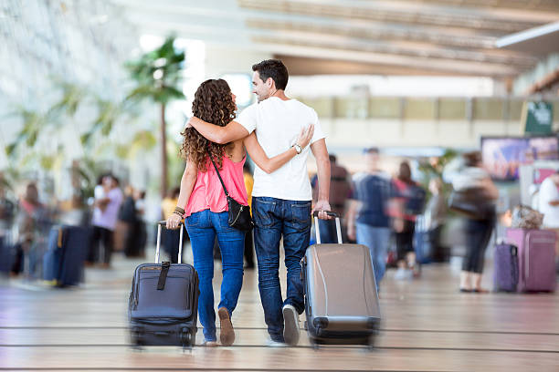 Couple with suitcases inside airport Young couple in a crowded airport, walking to their gate. man touching womans buttock stock pictures, royalty-free photos & images