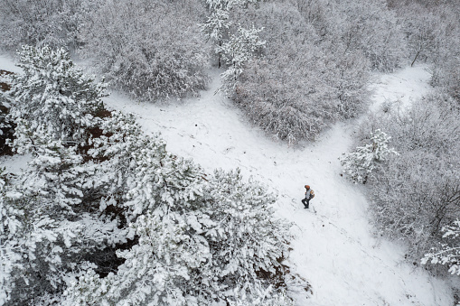 One man walking alone through the snow mountains, drone point of view
