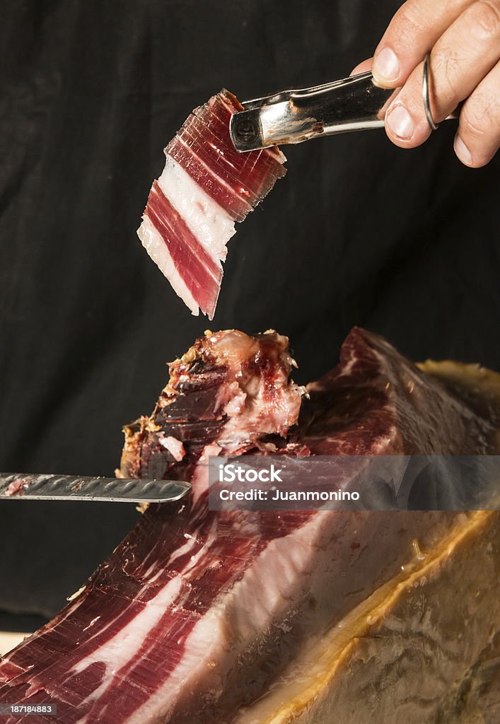 Chef posing cutting Cured Ham Chef hand holding a slice of Cured Spanish Iberico Serrano Ham Serrano Ham Stock Photo