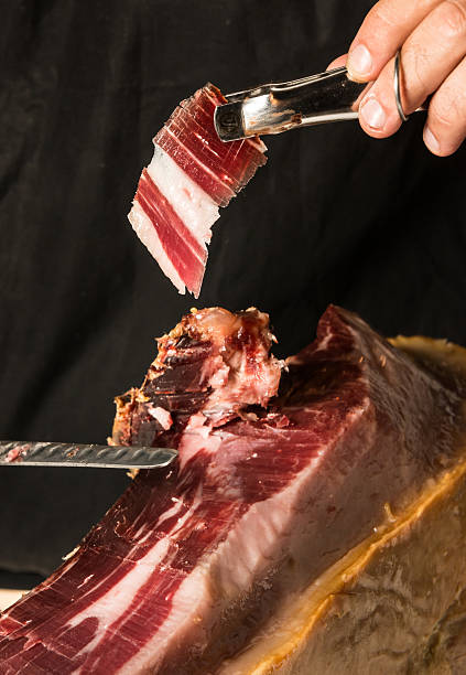 шеф-повар, которые позируют режущих копчёный окорок - ham kitchen knife meat iberian стоковые фото и изображения