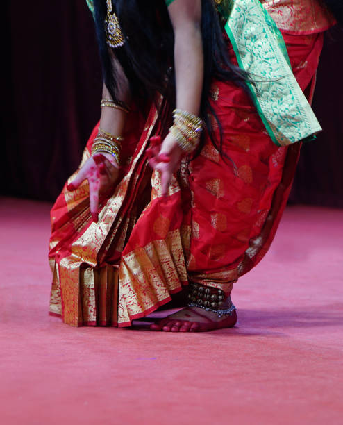 The bride gracefully, looking directly at the camera while proudly displaying her green bangles during her pre-wedding rituals. Her hands, decorated with intricate mehndi, highlight the beauty of the traditional jewelry.