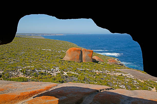 Spectacular view from Remarkable Rocks The spectacular view from Remarkable Rocks in Flinders Chase National Park, Kangaroo Island.  Looking through a rocky overhang to the rugged coastline with dense trees and huge coloured rock formations.  Contrast between red rocks, green foliage and blue ocean.  Horizontal, copy space. feldspar stock pictures, royalty-free photos & images