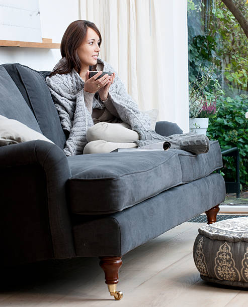 istock young woman on sofa drinking tea 187186157