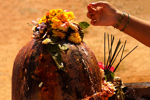 Close-up view of Indian Hindu woman offer prayers to stone carved god Shiva in shape of Lingam on maha shivaratri