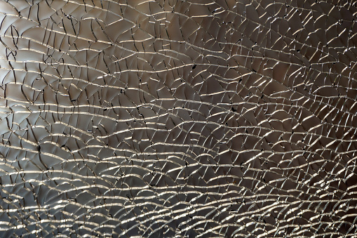 A network of broken glass cracks. Background. Texture. Glare of bright light