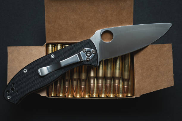 istock Tactical folding knife and rifle cartridges. Close up. 1871894710