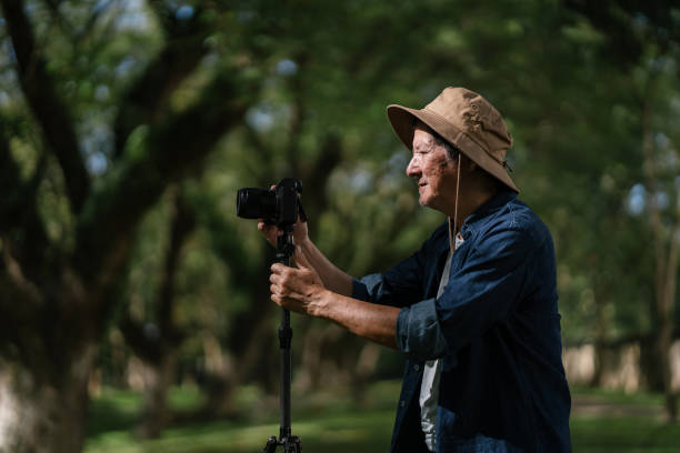 istock Senior Asian man captures nature beauty using camera and tripod. 1871895262