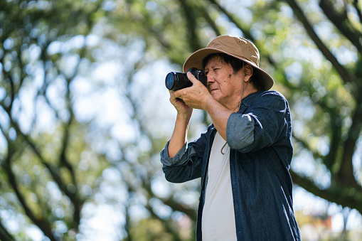 Senior Asian man capturing the beauty of nature with a mirrorless camera