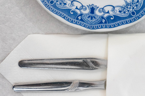 Vintage blue-toned dish with wrapped cutlery in a traditional restaurant setting.