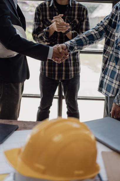 istock Architect engineer holding hands next to window, business teamwork, architect and engineer, construction workers holding hands while working and cooperation concept after completing agreement. 1871951530