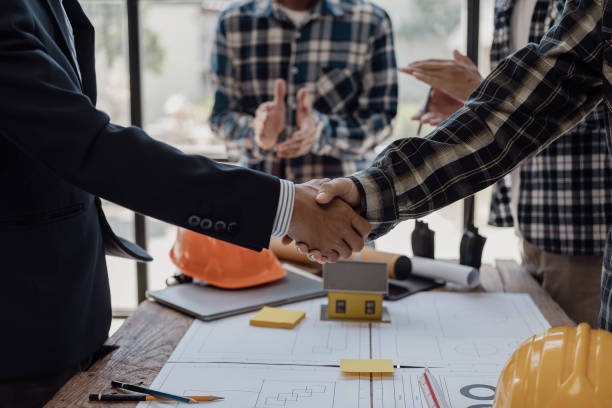 istock Architect engineer holding hands next to window, business teamwork, architect and engineer, construction workers holding hands while working and cooperation concept after completing agreement. 1871951532