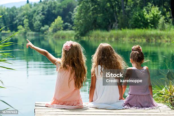 Three Girl Friends Together On River Jetty Stock Photo - Download Image Now - Sitting, Child, Friendship
