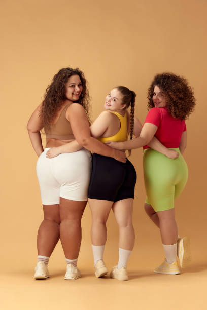 istock Back view of three smiling young omen, plus size models in comfortable sportswear over beige studio background 1871988774
