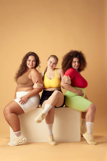 istock Three beautiful young women, plus size models with oversized bodies, posing in sportswear over beige studio background 1871988784